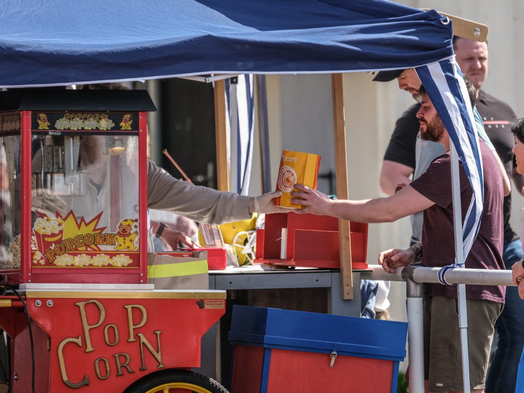 Popcorn-Stand des Fördervereins am Spieltag. Ein Mann bekommt gerade seine Portion Popcorn überreicht.